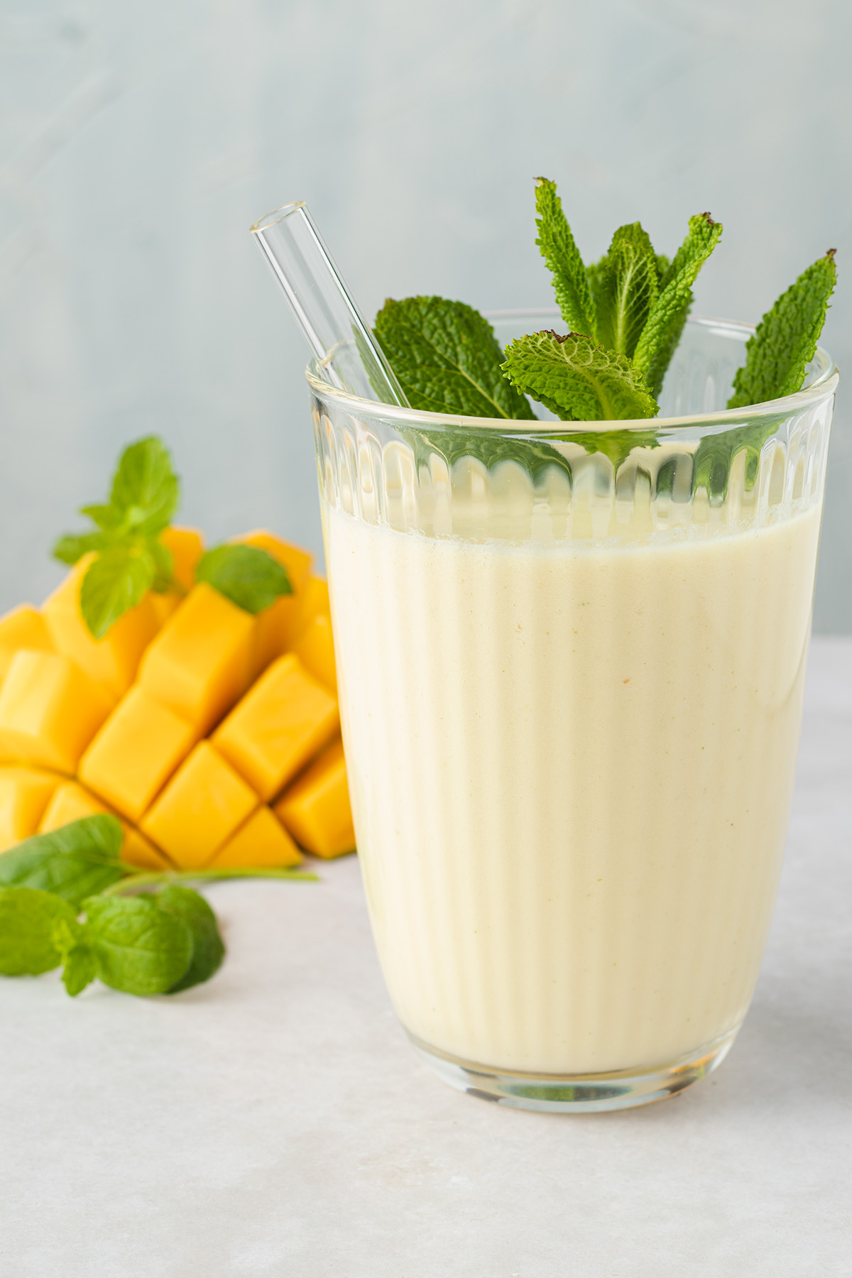 Ananas Smoothie mit Mango in einem Trinkglas mit Strohhalb und frischer Minze