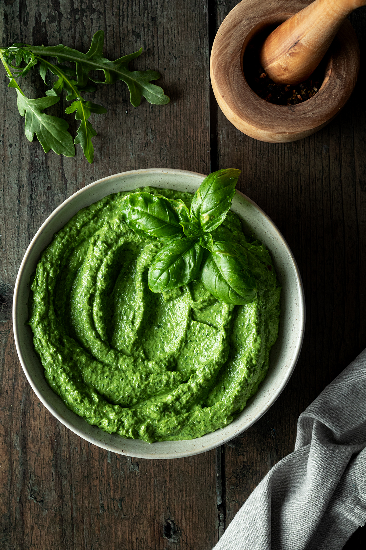 Cremige Avocado Pesto mit Deko auf einem Holztisch.