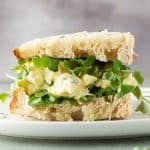 Eiersalat-Sandwich mit Sprossen auf einem Teller.