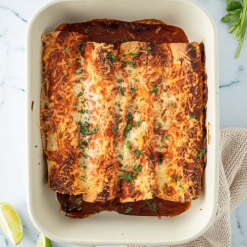 Vogelperspektive auf eine Auflaufform mit Käse überbackenen Enchiladas, Deko im Bildrand.