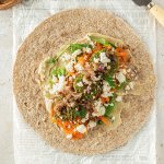 Ein offener Falafel Wrap auf hellem Untergrund mit Deko im Bildrand.