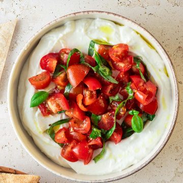 Cremiger Feta-Dip mit Bruschettaw&uuml;rfel, Pita und Tomaten im Bildrand.