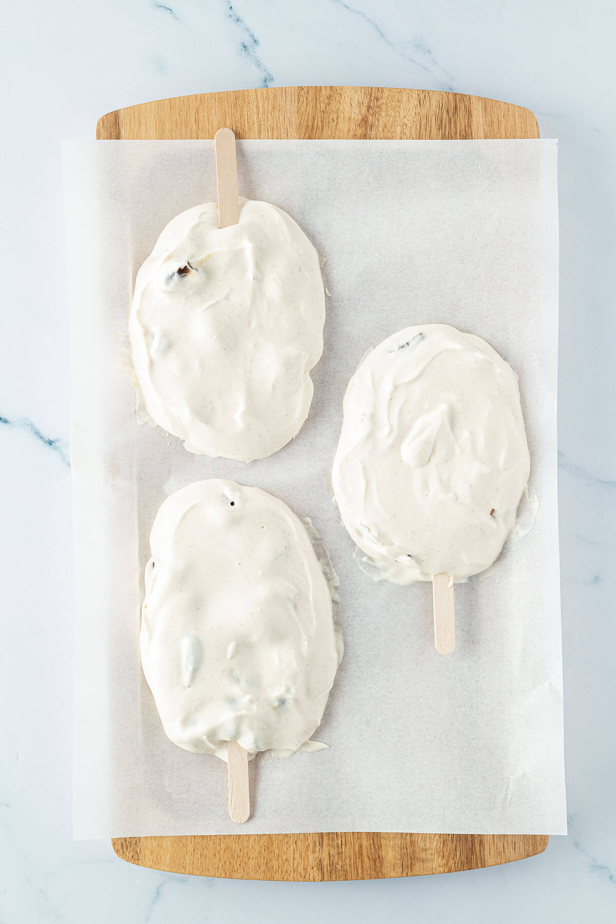 Eiscreme in auf drei H&auml;ufchen verteilt mit je einem Holzst&auml;bchen.