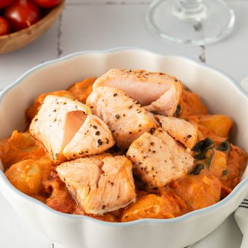 Cremige Gnocchi mit Lachs in tomatiger Marry Me Sahnesauce, angerichtet in einer weißen Schüssel auf hellem Untergrund.