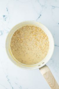 Nudeln kochen in einem Topf mit milchiger Flüssigkeit.