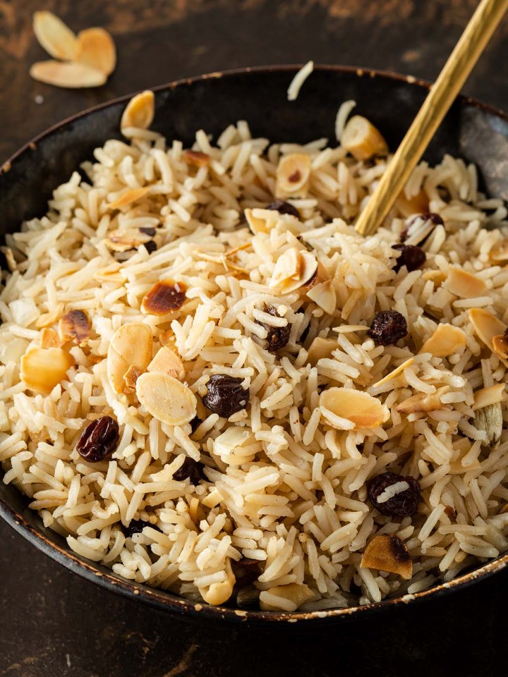 Nahaufnahme von einer Sch&uuml;ssel mit lockerem Basmati Reis mit Rosinen und Mandeln.