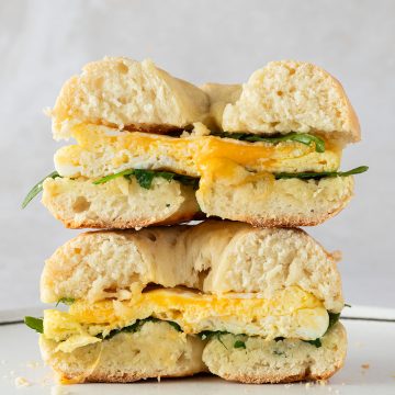 Ein übereinander gestapeltes Bagel Sandwich mit Ei und Rucola.