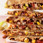 Ein Stapel Quesadilla mit Hackfleisch, wo eine Hand einen Quesadilla wegnimmt.