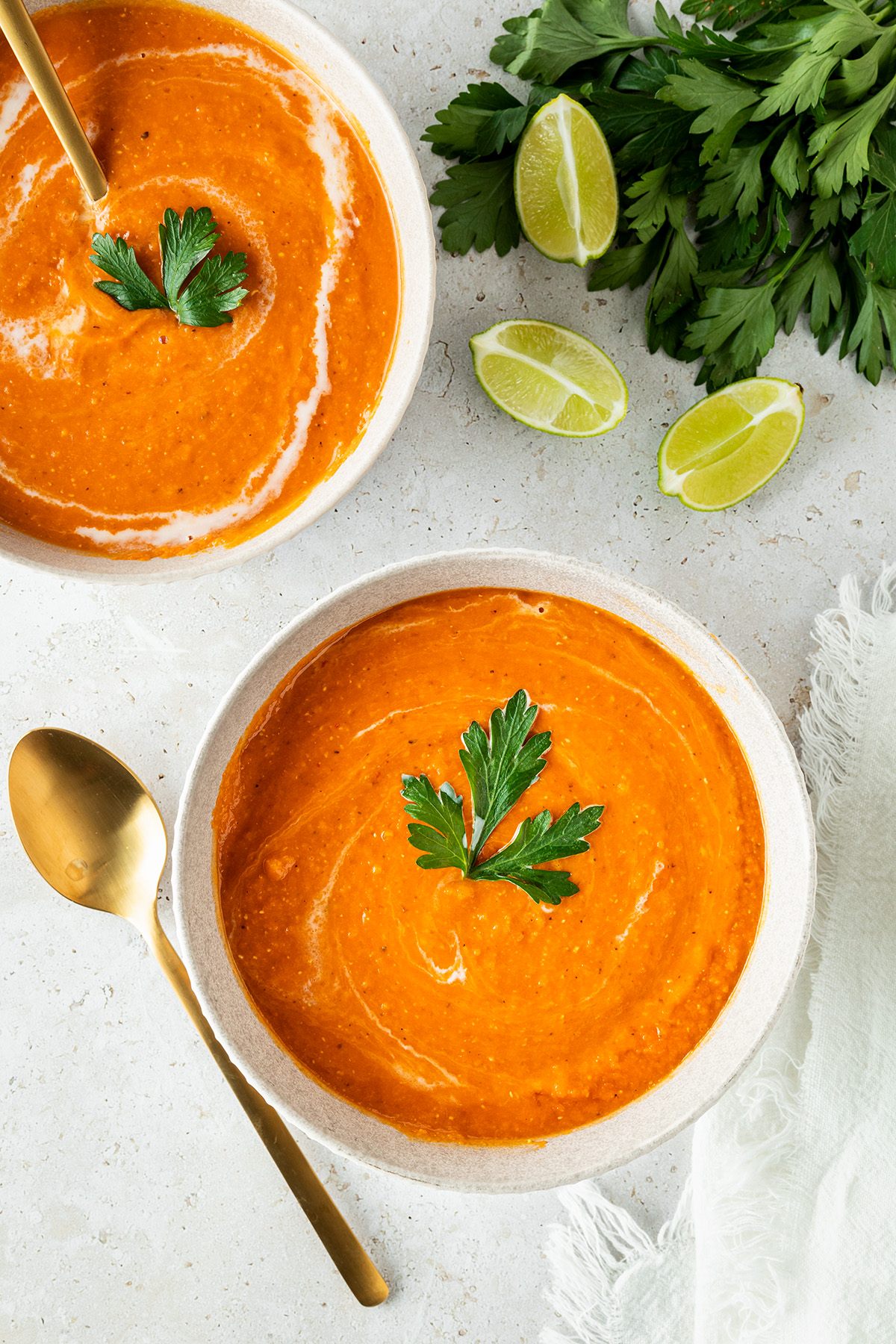 Zwei Sch&uuml;sseln mit cremiger rote Linsensuppe mit Kokosmilch, serviert mit Limette und frischem Koriander.