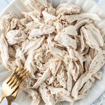 Nahaufnahme von einem Teller mit Pulled Chicken, zwei goldene Gabeln im Bildrand.