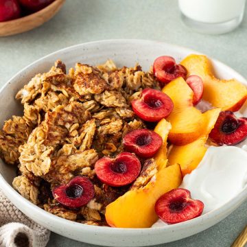 Scrambled Oats in einem Teller mit frischem Obst und Joghurt, Deko im Bildrand.