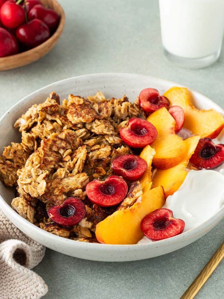 Scrambled Oats in einem Teller mit frischem Obst und Joghurt, Deko im Bildrand.