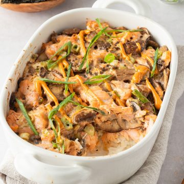 Sushi Auflauf in einer Auflaufform, Nori-Blätter und Frühlingszwiebeln im Hintergrund.