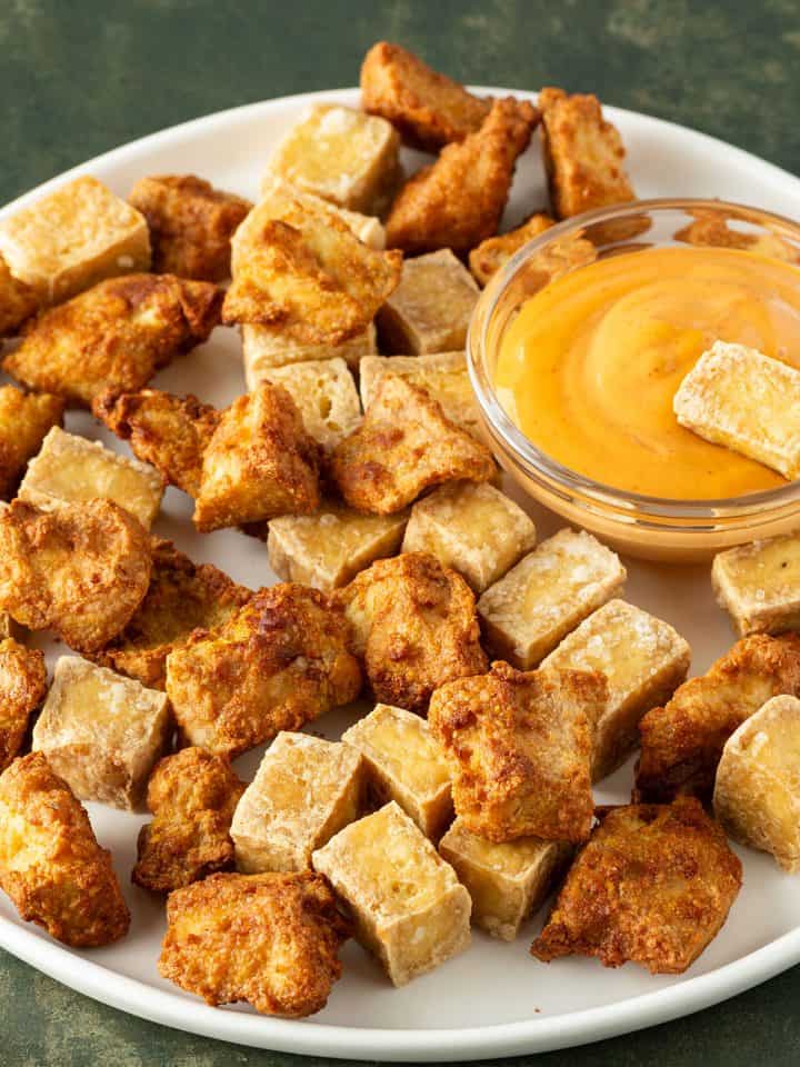 Knusprige Tofuw&uuml;rfel mit und ohne Marinade aus der Hei&szlig;luftfritteuse auf einem Teller mit Dip.