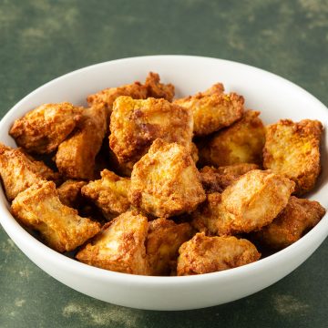 Knusprige, marinierte Tofuw&uuml;rfel aus dem Airfryer in einer wei&szlig;en Sch&uuml;ssel.