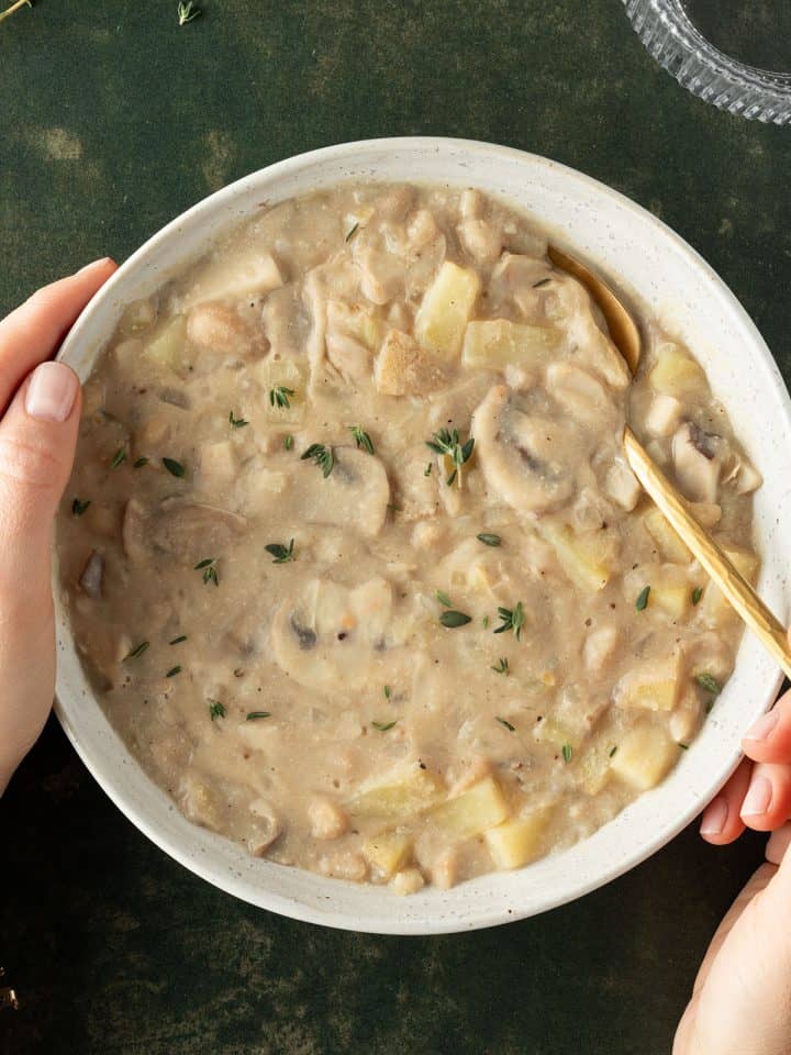 Wei&szlig;er Bohneneintopf mit Pilzen und Kartoffeln in einem tiefen Suppenteller.