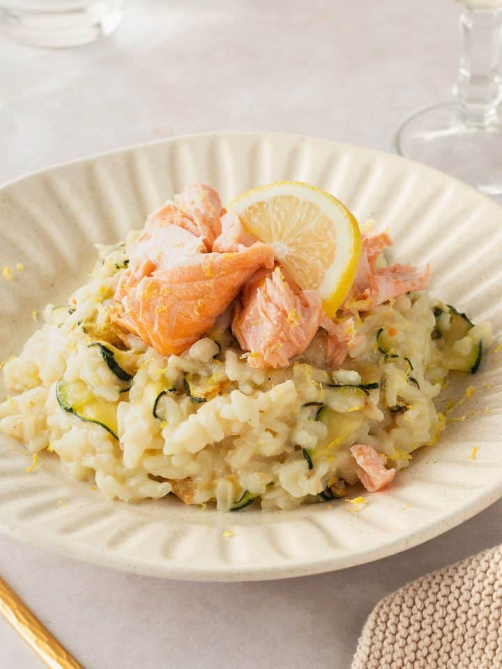Ein Teller mit cremigen Risotto mit Zitrone, Zucchini uns saftigem Lachsst&uuml;ckchen.