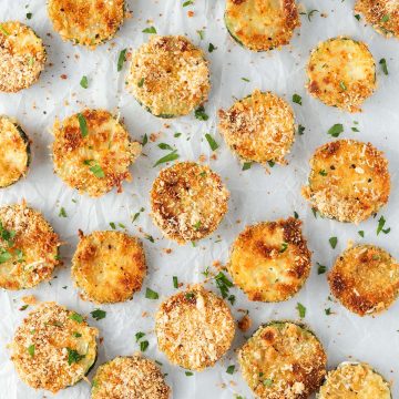 Knusprige Parmesan Zucchini Chips auf weißem Backpapier.