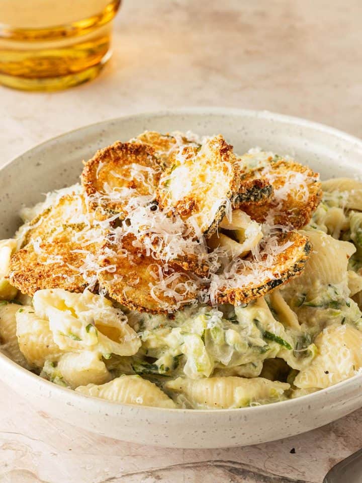 Cremige Zucchini Pasta mit Ricotta und knusprigen Zucchini-Chips, serviert mit frisch geriebenem Parmesan.